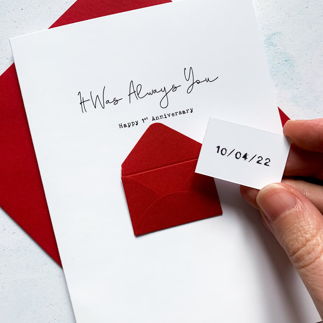 A personalised 1st anniversary greeting card featuring a secret message hidden inside a red mini 3d envelope on the front of the card. Text on the front reads It Was Always You, with the wedding date on the mini token inside the tiny envelope