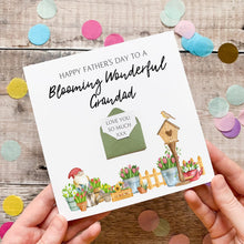 Load image into Gallery viewer, A hand holding a greeting card with a floral design and a birdhouse, surrounded by confetti.