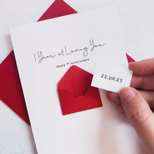 Load image into Gallery viewer, A hand holding a white card with a red envelope and a small white card attached to it, with the date "22.08.23" written on the small card.