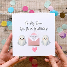 Load image into Gallery viewer, a person holding a birthday card with a ghost and a heart, surrounded by colorful confetti on a wooden surface.