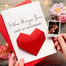 Load image into Gallery viewer, A handmade card with a red heart-shaped origami and a photograph of a couple embracing, placed on a wooden surface with pink flowers.