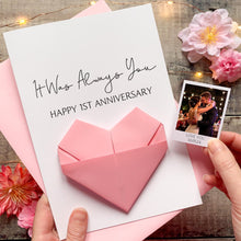 Load image into Gallery viewer, A handmade card with a pink heart-shaped origami and a photograph of a couple embracing, placed on a wooden surface with pink flowers.